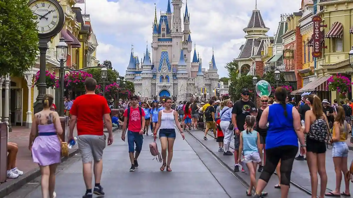 Crowds of visitors walking along Main Street at Disney World, with Cinderella Castle in the distance on a sunny day