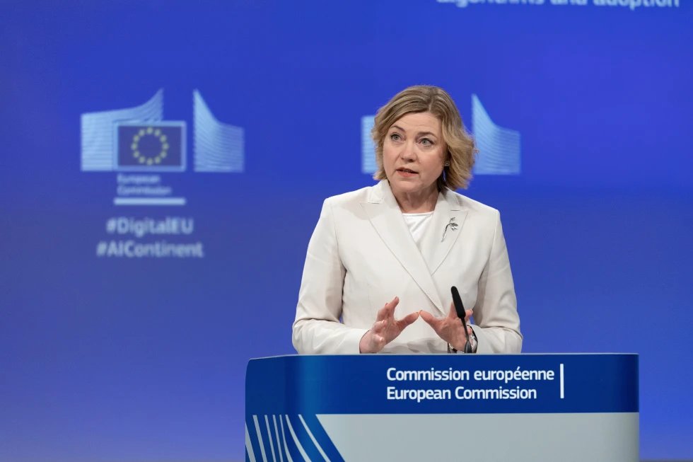 European Commissioner for Digital Infrastructure giving a speech at a European Commission event, with digital transformation themes in the background.
