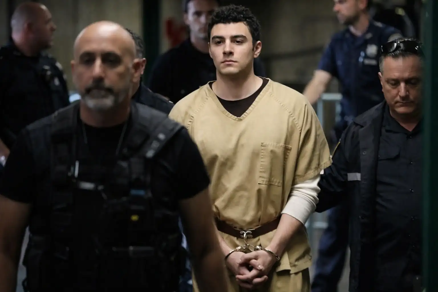 Luigi Mangione in custody, escorted by law enforcement after his arrest in the Brian Thompson killing investigation.