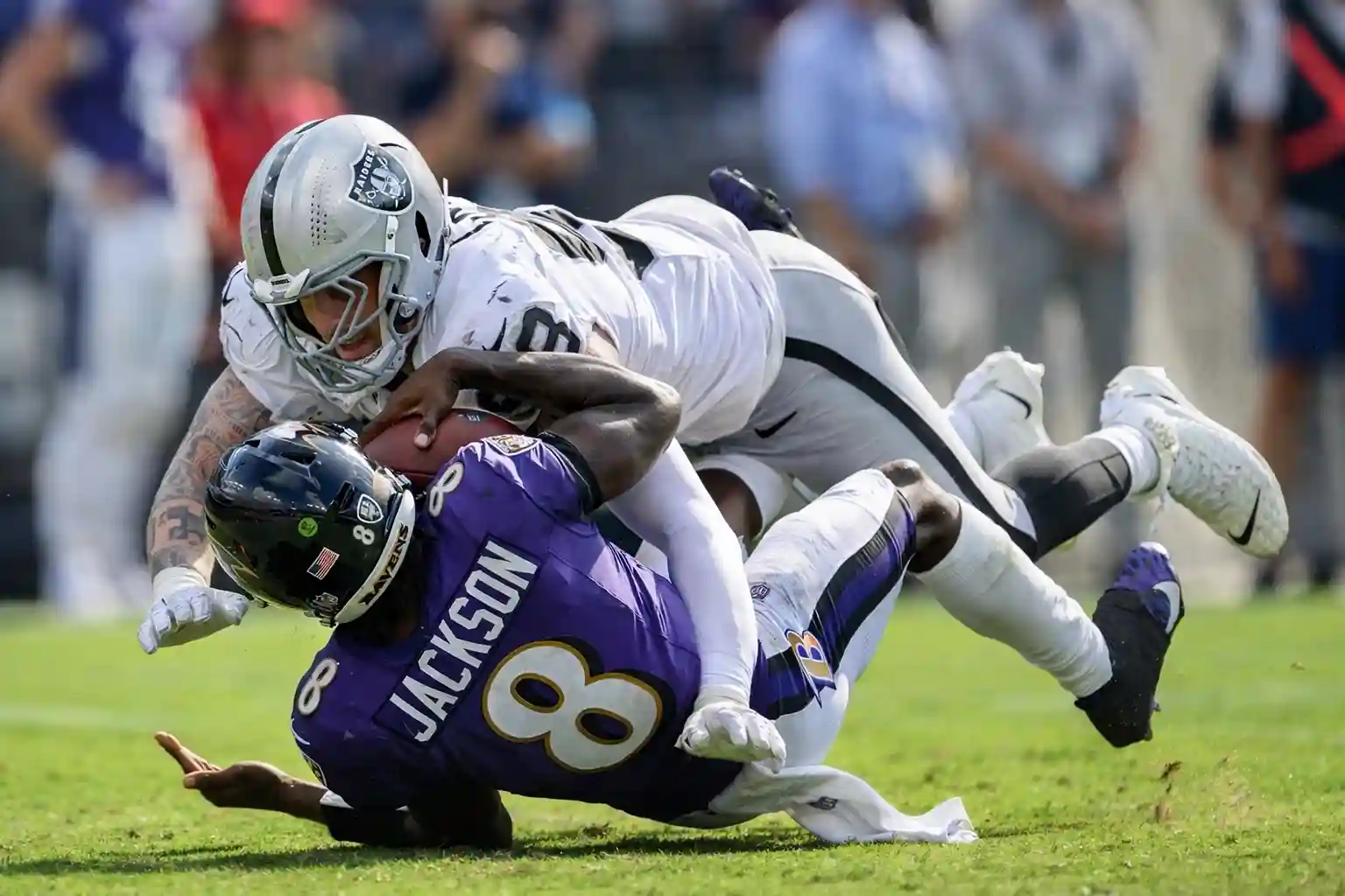 Las Vegas Raiders pass rusher Maxx Crosby sacks Baltimore Ravens quarterback Lamar Jackson during an NFL game.
