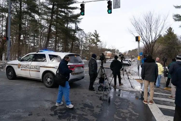 Police SUV with lights on and news crews stationed at a snowy intersection near Thomas S. Wootton High School during the emergency response.